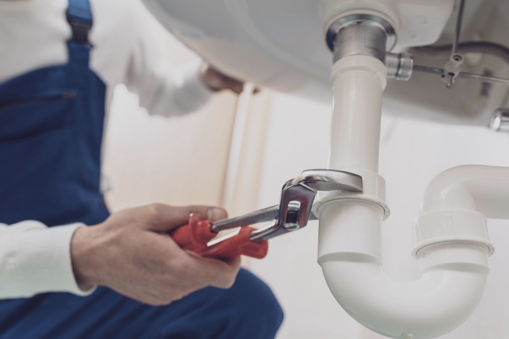 A plumber fixing a pipe with a wrench