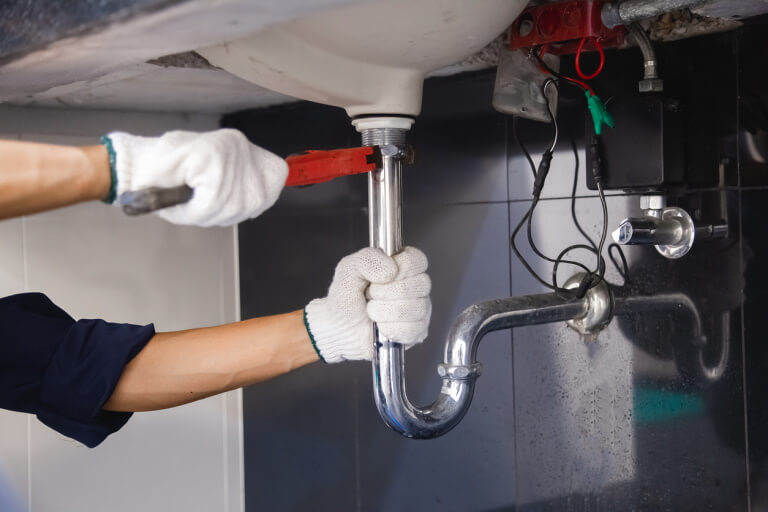 Plumber fixing white sink pipe