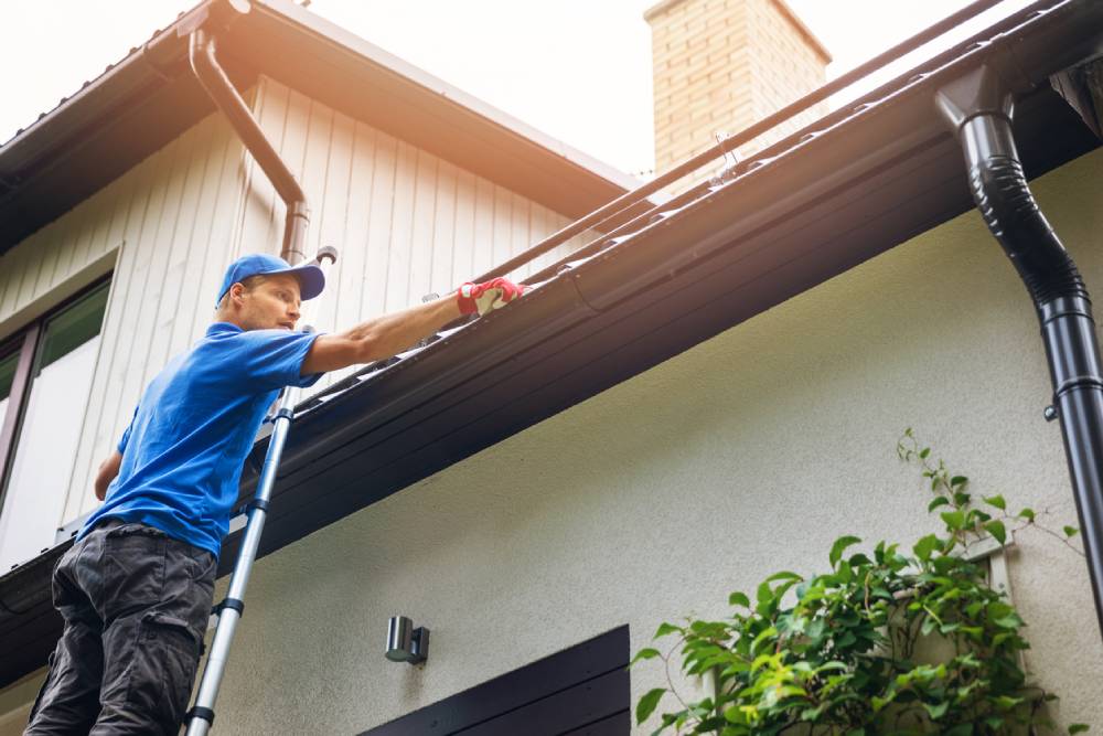 Man inspecting the gutters on a roof