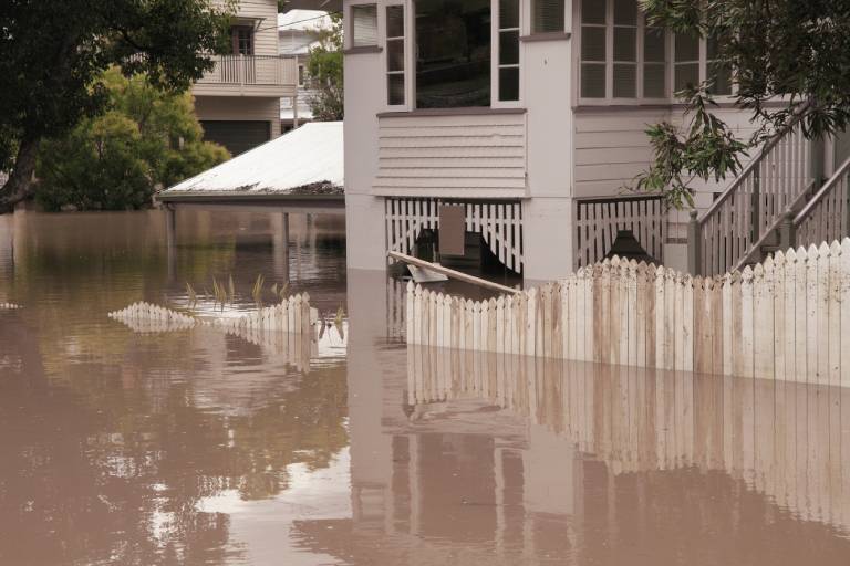 Flood water reaching half the height of a home's fence.