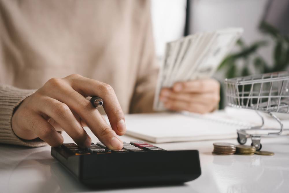 Woman doing finances: holding money and using a calculator