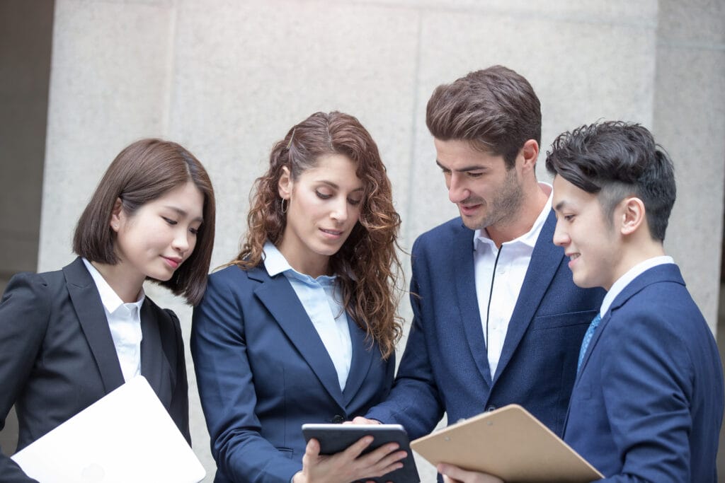 Four public adjusters in los angeles in suits discussing something in the tablet