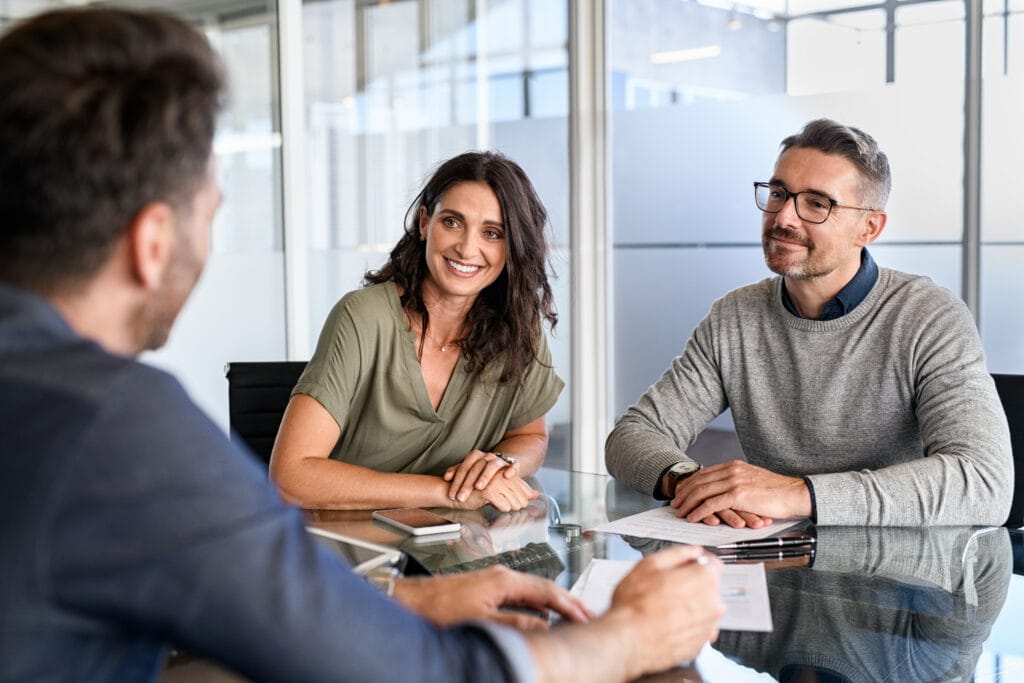 Happy middle age couple sitting in the office in front of public adjuster in long beach