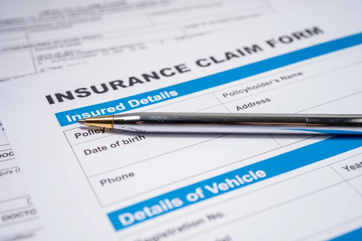 Insurance claim form with a large red "DENIED" stamp, placed on a desk next to a keyboard and pen