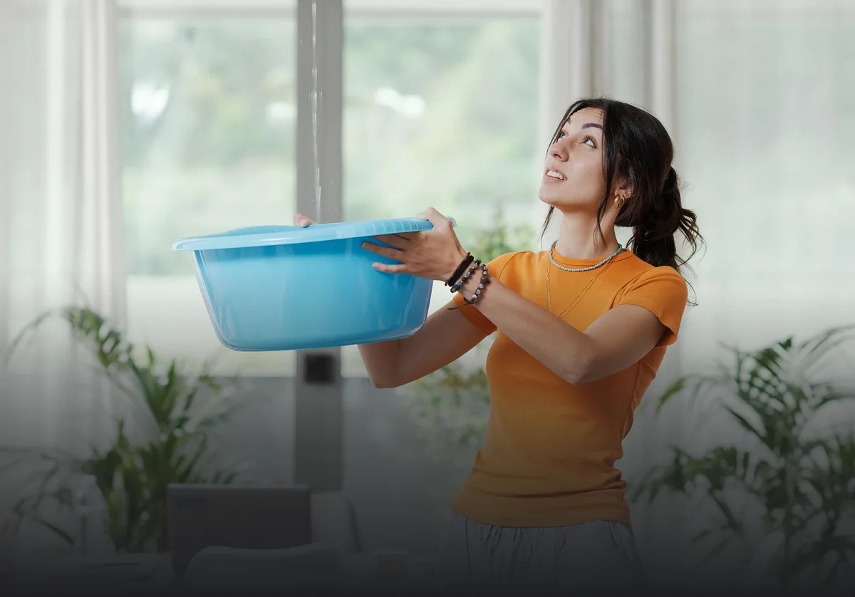 woman holding a blue basin under a ceiling leak