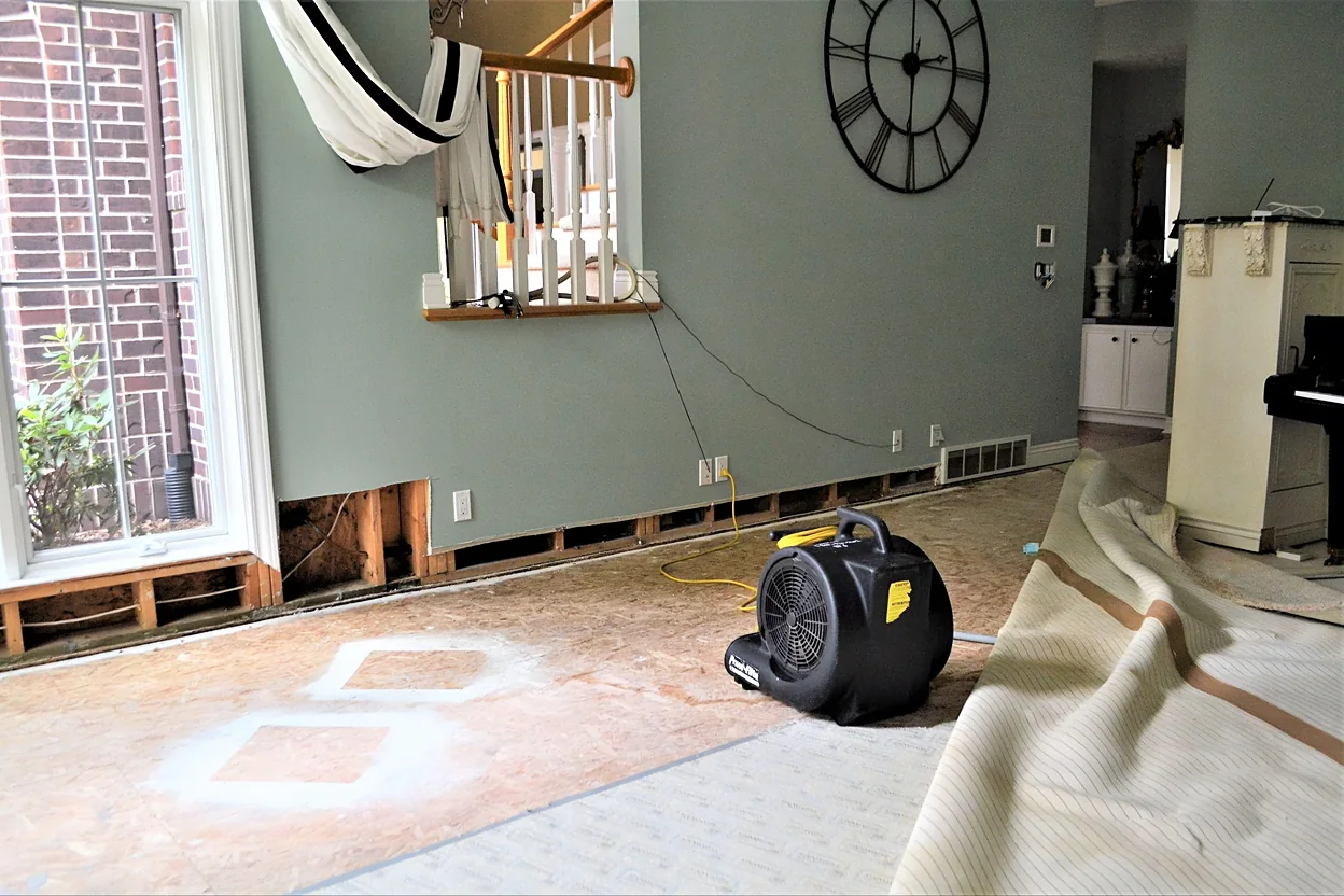 water-damaged room with a drying fan on the floor