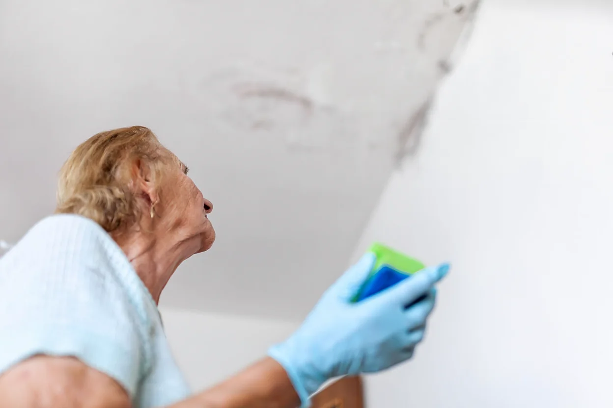 woman wiping a water stain on a wall